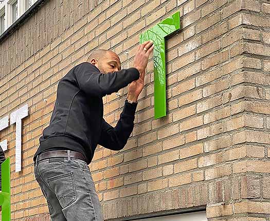 montage van gevelletters en freesletters tegen een buitenmuur van een pand