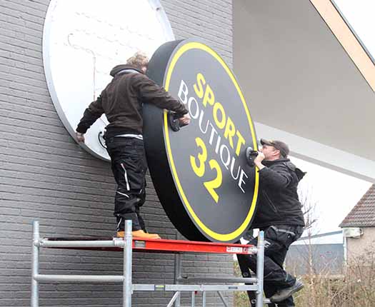 montage van ronde lichtbakken aan de gevel van een gebouw